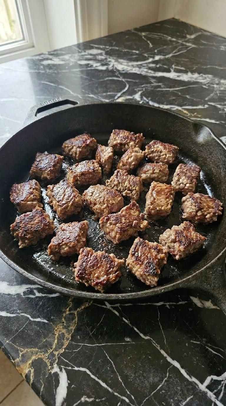 Ground beef browning with crispy edges in a cast iron skillet