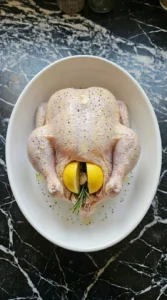 Halved lemons and garlic cloves stuffed inside the cavity of a raw seasoned chicken