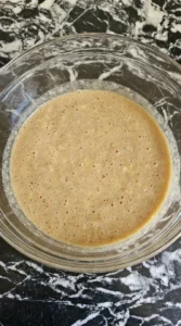 Bubbly light brown liquid mixture of wet ingredients in a glass bowl
