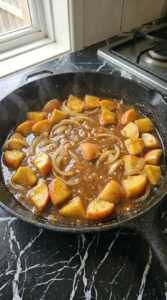 Glossy apple butter pan sauce reducing with Honeycrisp apples and onions