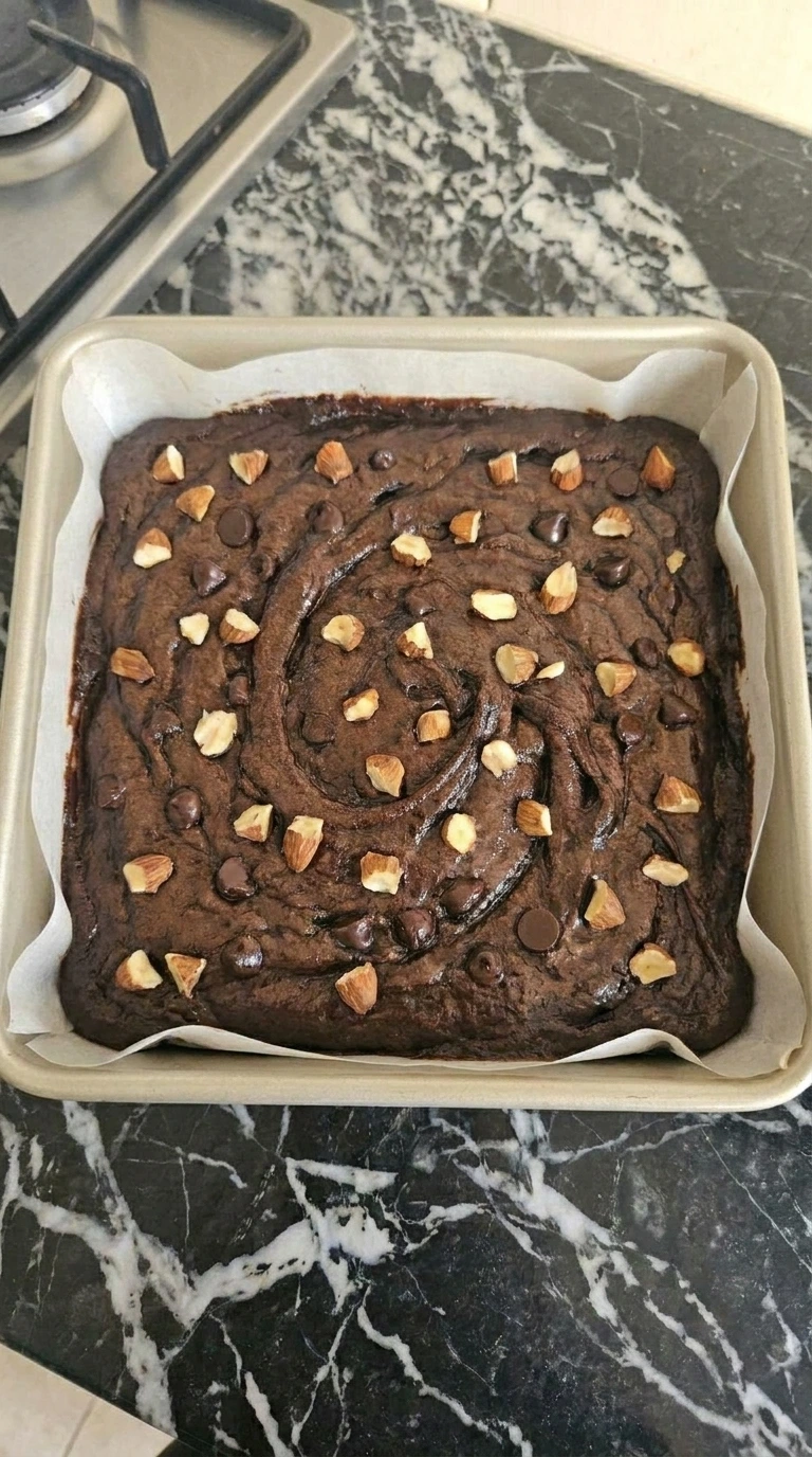 Baked sweet potato brownies with a crackled cocoa top and melted chocolate chips.