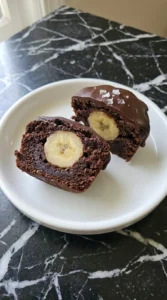 Banana Brownie Bites finished with glossy chocolate and one cut open to reveal the banana center