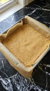 Pressing graham crust for Banana Cheesecake Bars in square pan Recipe focus: symboles.