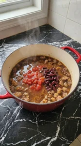 Adding beans and liquid to Boilermaker Tailgate Chili: The Hearty One-Pot Game Day Recipe Recipe focus: Purdue Boilermaker Chili.