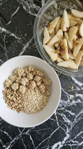 Oat walnut topping clusters for Caramel Pear Crisp in a white mixing bowl.