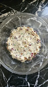 Folding the creamy filling for Cranberry Pecan Cheese Ball with cheddar, cranberries, pecans and chives