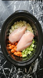 Layering raw chicken and diced vegetables for Cream of Chicken Soup Recipes Crockpot Families Can Make on Busy Nights.