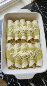 Adding sauce and Monterey Jack to Creamy Hatch Green Chile Chicken Enchiladas