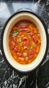 Easy Slow Cooker Tomato Soup for Cozy Fall Dinners as the chunky San Marzano tomato base softens in a cream ceramic slow cooker insert