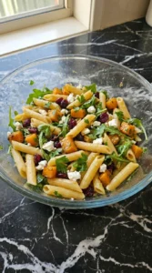 Fall Pasta Salad Recipes with Cozy Harvest Flavor step showing penne folded with roasted squash, cranberries, arugula and feta.