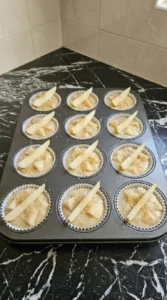 Twelve unbaked Cinnamon Pear Muffins topped with pear wedges and demerara sugar