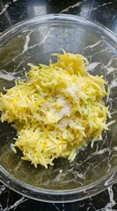 Coarsely grated yellow patty pan squash resting with kosher salt