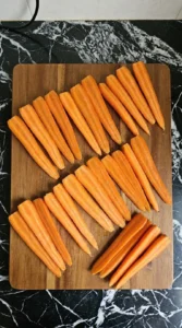 Twenty-four raw carrot halves cut lengthwise for roasting
