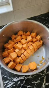 Simmered sweet potato cubes for Maple Sweet Potato Mash in a stainless steel pot