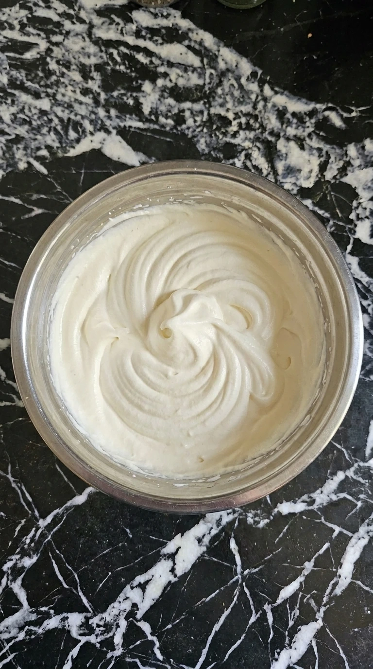 Soft vanilla whipped cream for Neapolitan Ice Cream Sundae (Strawberry, Chocolate & Vanilla) with curled peaks in a metal bowl.