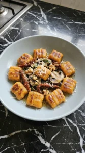 Single bowl of Sweet Potato Gnocchi with mushrooms walnuts herbs and Parmesan.