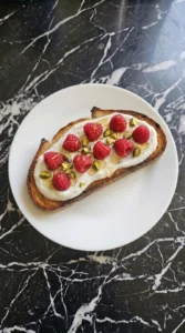 Adding fresh raspberries and nuts to assemble Raspberry Yogurt Toast
