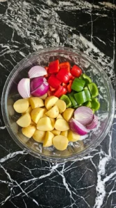 Cut potatoes and peppers for Sheet Pan Chicken Thighs and Potatoes for an Easy Dinner in a glass bowl