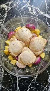 Sheet Pan Chicken Thighs and Veggies for Busy Weeknights step 2 with chicken thighs, potatoes and onion coated in herb Dijon seasoning