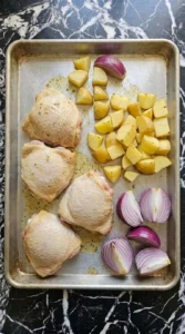Sheet Pan Chicken Thighs and Veggies for Busy Weeknights step 3 with chicken skin turning pale gold and potato bottoms beginning to brown