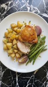 Sheet Pan Chicken Thighs and Veggies for Busy Weeknights step 5 with one sliced chicken thigh, roasted potatoes, green beans and onion