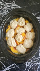 Slow Cooker Peach Cobbler with Fresh Summer Peaches step 3 layered with fresh peach filling and uneven batter mounds