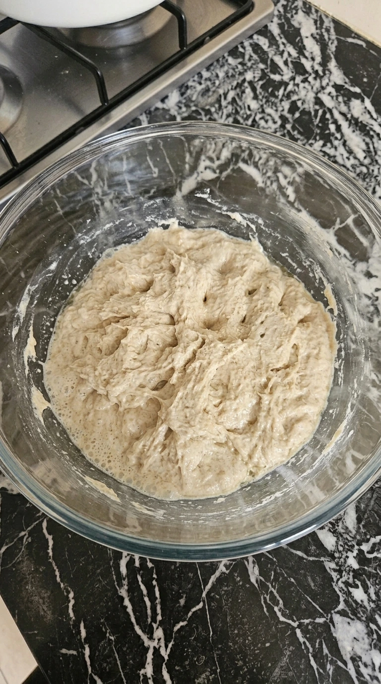 Mixing the sticky dough for Sourdough Discard Focaccia (Easy No-Waste Recipe) in a clear glass bowl
