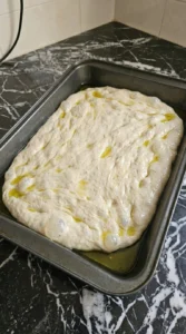 Stretching Sourdough Discard Focaccia (Easy No-Waste Recipe) dough into an oiled 9×13-inch pan