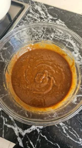Glossy sweet potato brownie wet mixture in a clear glass bowl.