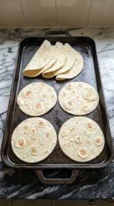 Eight flour tortillas warming until soft and lightly blistered