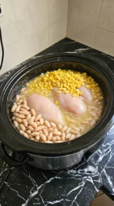 Crockpot Healthy White Chicken Chili step 1 with chicken beans and broth combined Recipe focus: white chicken chili with rotisserie.