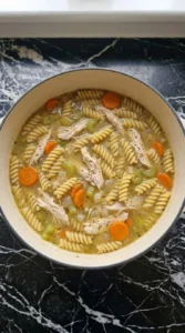 Brown rice rotini and shredded chicken simmering in Gluten Free Chicken Noodle Soup