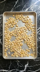 Roasted Pumpkin Seeds with Parmesan Cheese step showing pumpkin seeds turning golden in the oven