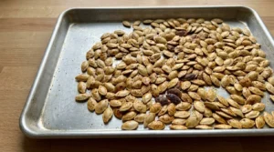 Roasted Pumpkin Seeds with Parmesan step four showing golden pumpkin seeds with crisp bronze spots before adding Recipe focus: autumn roasted pumpkin seeds.