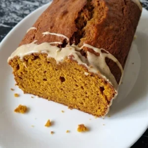 Brown Butter Pumpkin Bread with a cracked copper top, thin icing and one sliced end showing the moist pumpkin Recipe focus: brown butter pumpkin bread recipe.
