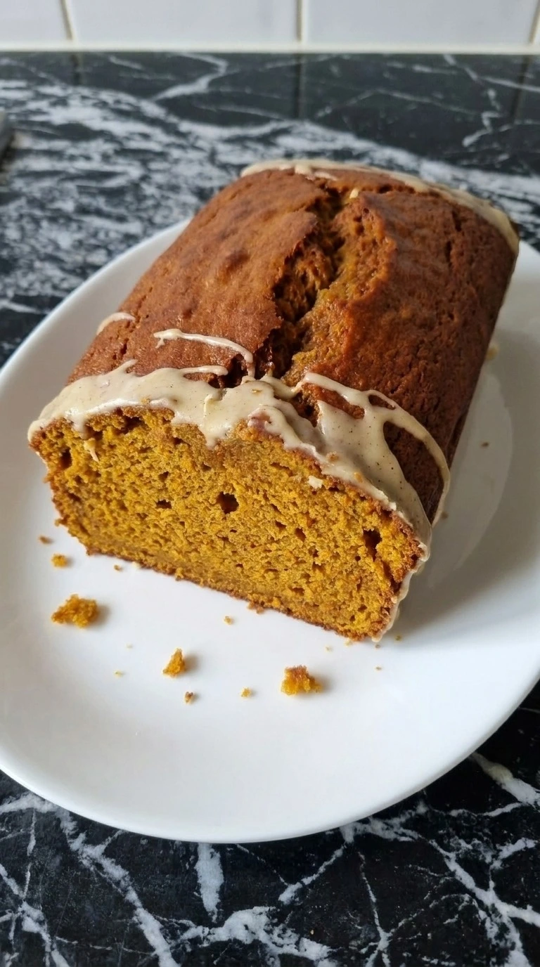 Brown Butter Pumpkin Bread with a cracked copper top, thin icing and one sliced end showing the moist pumpkin Recipe focus: brown butter pumpkin bread recipe.