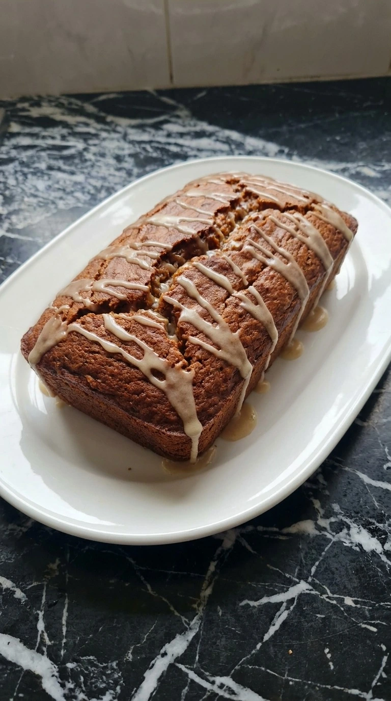 Brown Butter Pumpkin Bread cooled and topped with thin ivory brown butter icing over the cracked loaf Recipe focus: pumpkin banana bread recipe.