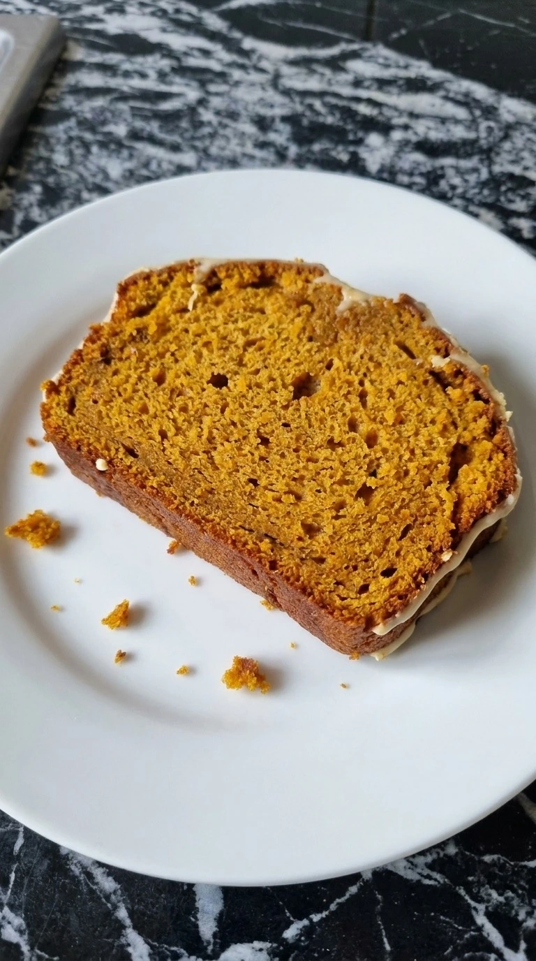 Brown Butter Pumpkin Bread slice showing moist orange crumb, spice flecks, copper crust and a thin layer of icing Recipe focus: pumpkin bread with icing.
