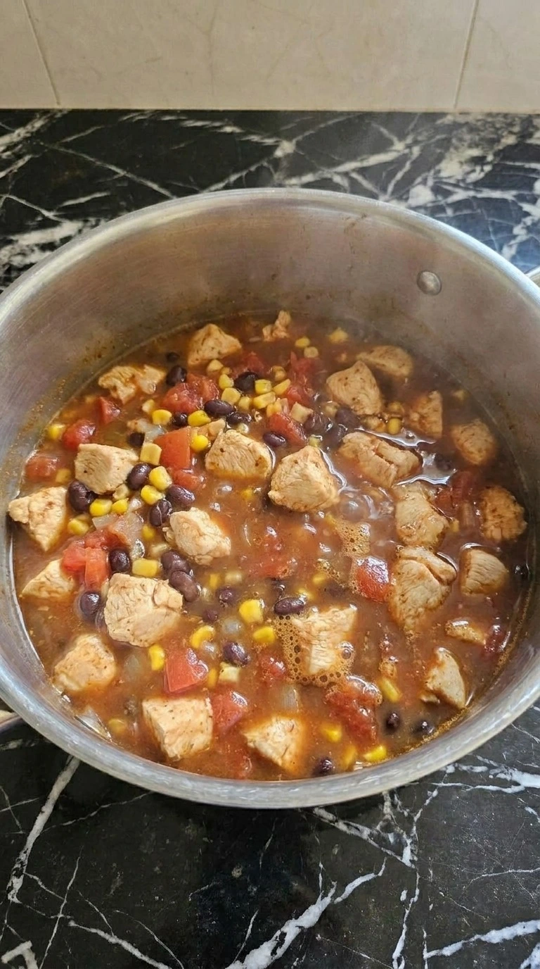 Chicken Taco Soup simmering with chicken beans and rich red broth Recipe focus: taco soup recipe.
