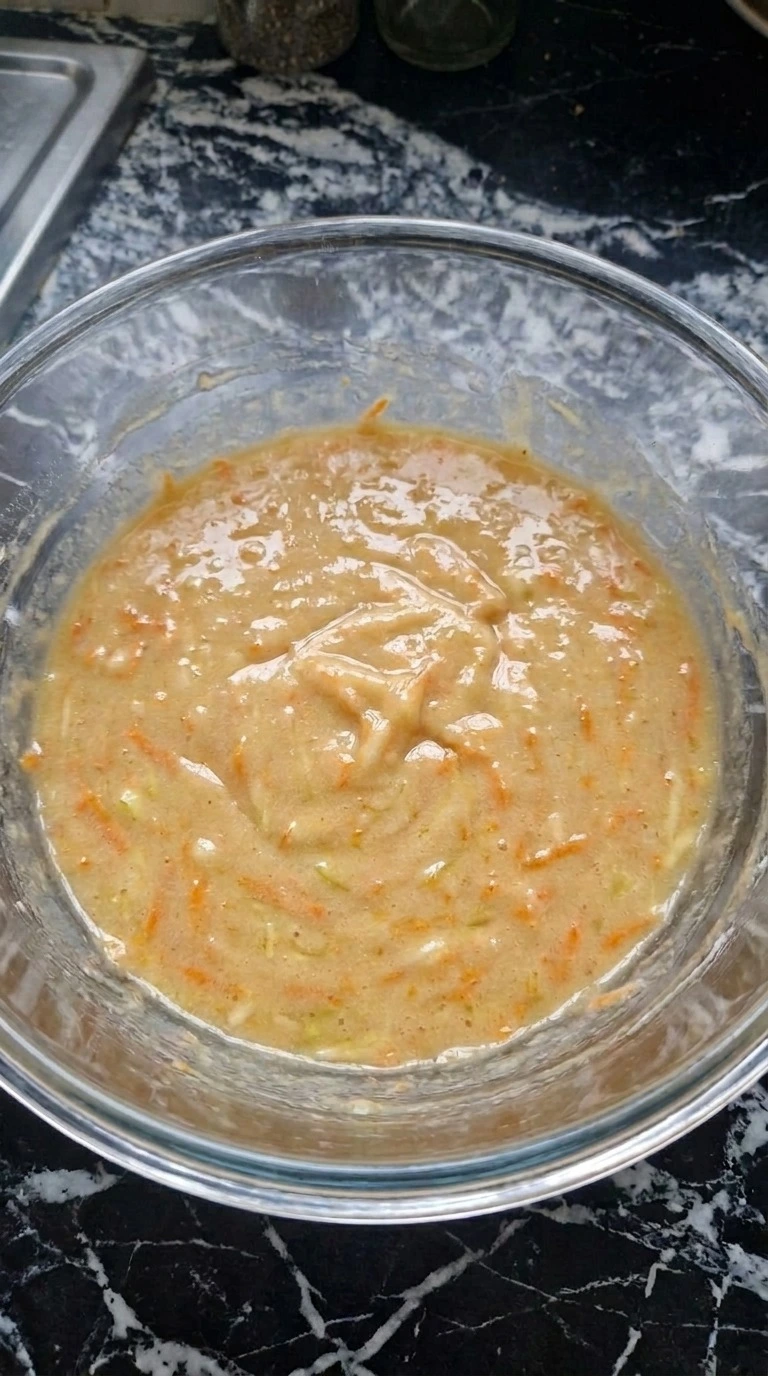 Folding spiced batter for Fall Desserts for People Who Hate Pumpkin with visible apple and carrot flecks