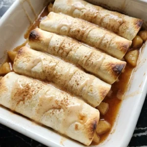 Fall Desserts with Apple Pie Filling shown as glazed cinnamon apple pie enchiladas in a white baking dish