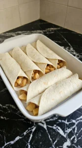 Fall Desserts with Apple Pie Filling step showing six apple-filled flour tortillas rolled in a baking dish