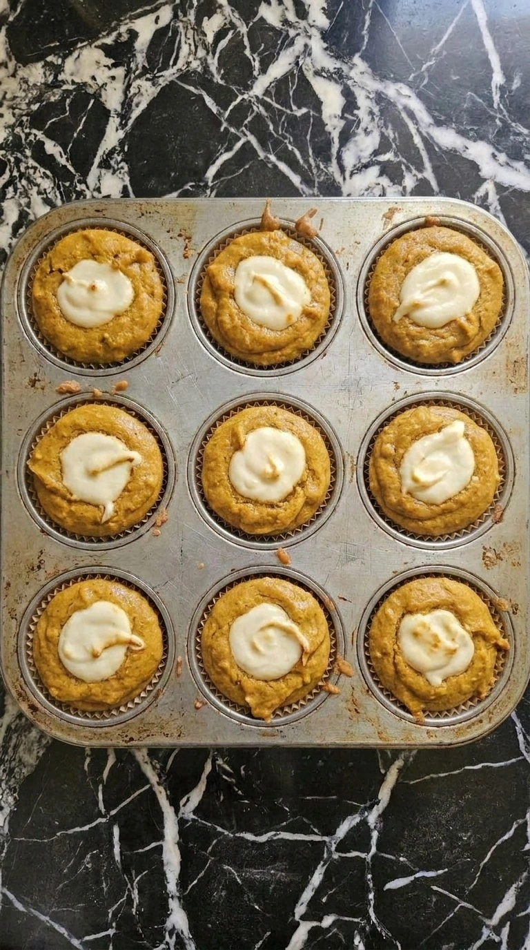 Fall Desserts with Cream Cheese baking as pumpkin muffins with golden edges and set cream cheese centers