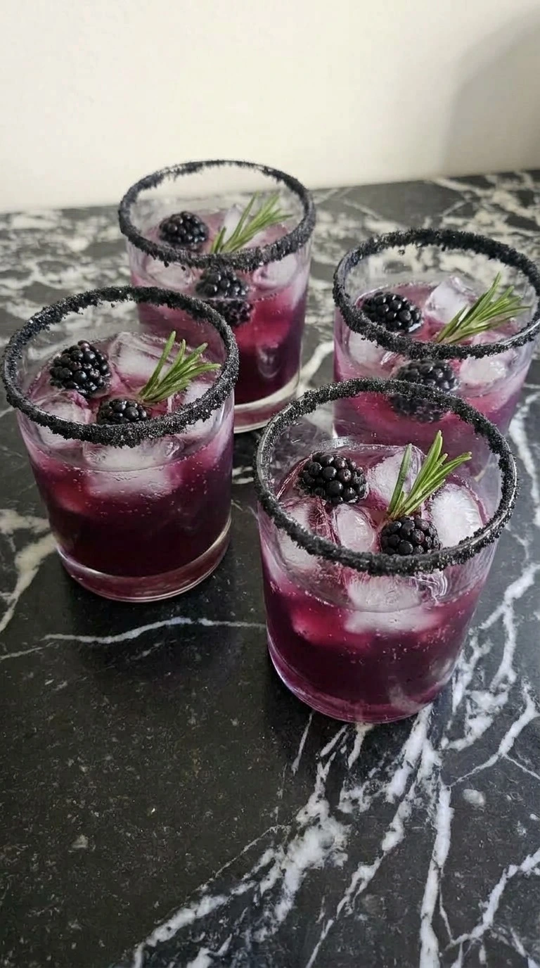 Halloween Cocktails finished with club soda bubbles, three blackberries and rosemary in each black-rimmed rocks Recipe focus: easy halloween cocktails recipes.