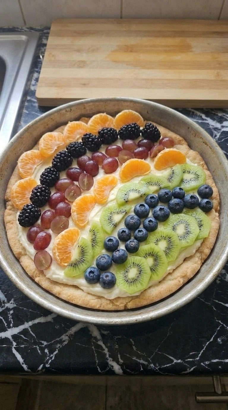 Halloween Fruit Pizza Sugar Cookie decorated with mandarin oranges, berries, green grapes and kiwi