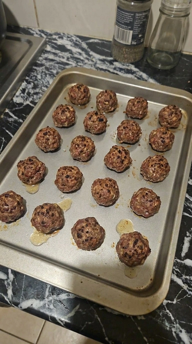 Halloween Party Food Meatballs with 16 beef meatballs baked to dark brown speckles on a tray
