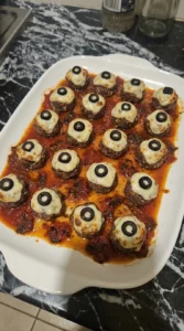 Halloween Party Food Meatballs topped with mozzarella eyes and black olive pupils on a serving platter