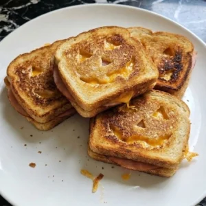Halloween Party Food Sandwiches with golden jack-o'-lantern bread, smoky ham and melted sharp cheddar.