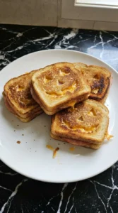 Halloween Party Food Sandwiches plated with uneven golden bread and melted cheddar glowing through crooked faces.