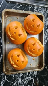 Halloween Pumpkin Carving step with four sugar pumpkins freshly hollowed and carved with simple faces. Recipe focus: easy halloween pumpkin carving.